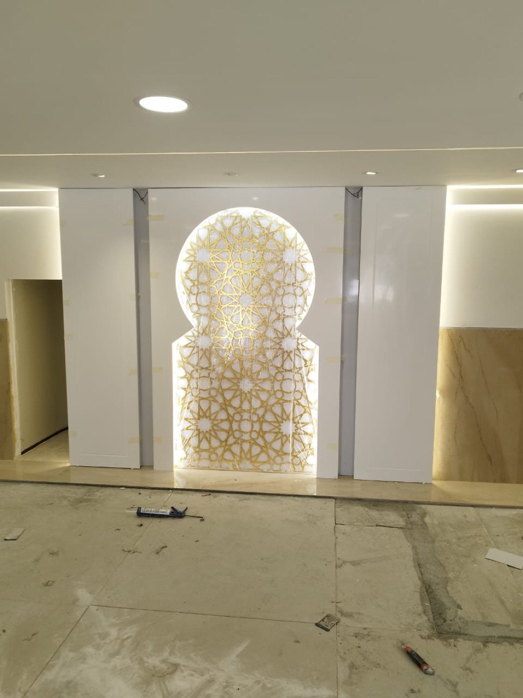 Backlit gold mashrabiya arch feature wall fabricated in solid surface, UAE fit-out project