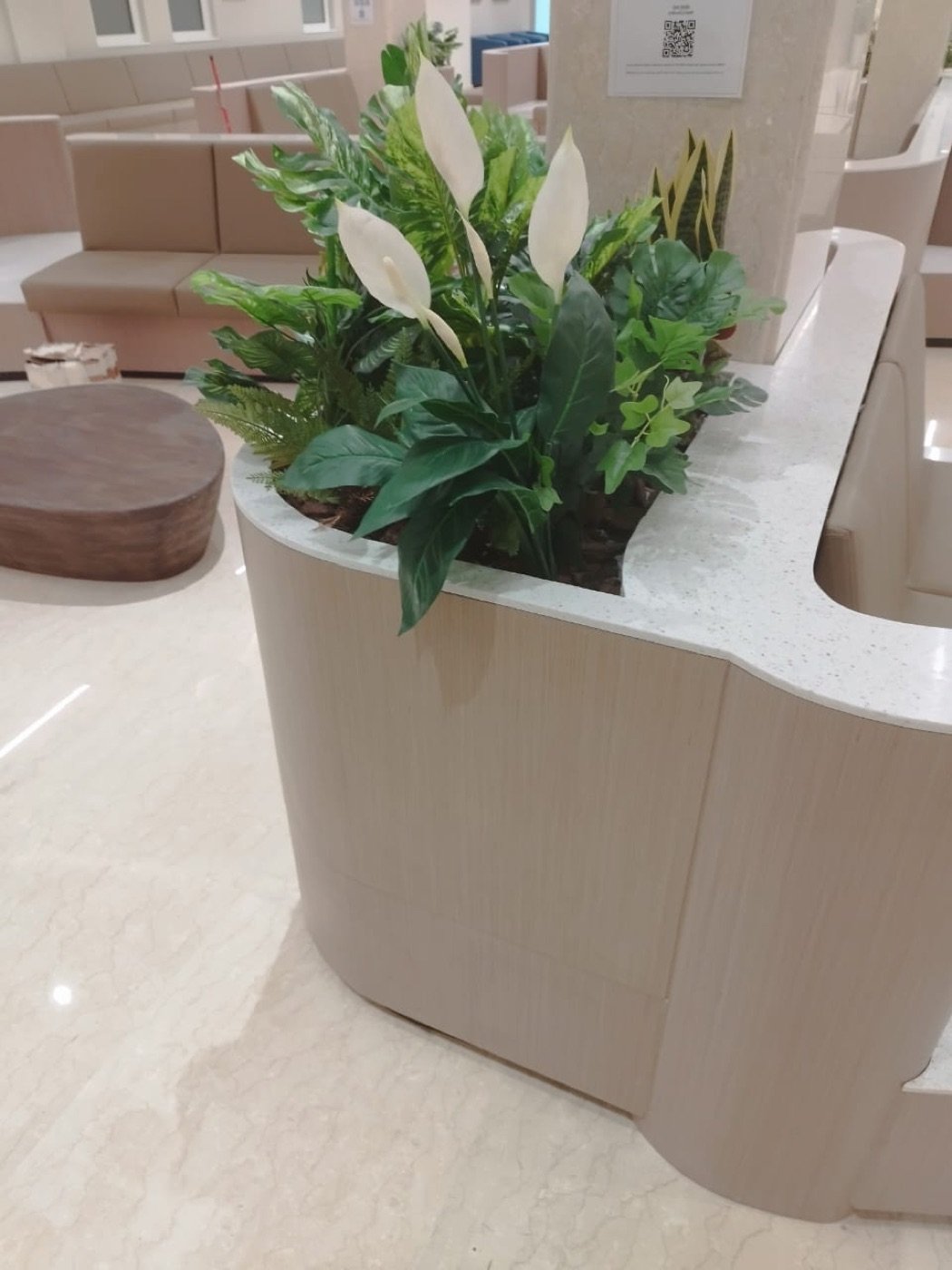 Curved solid-surface lobby bench with integrated planter, commercial fit-out UAE