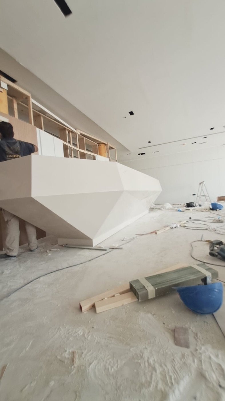 Large faceted solid-surface reception desk under installation in a UAE office