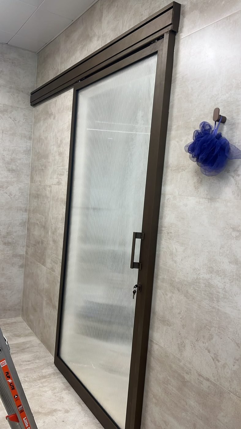 Angle view of the slim bronze frame sliding door against stone-look wall tiles
