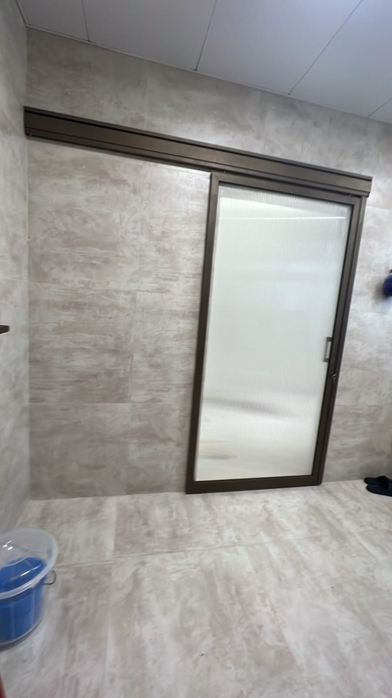 Closed fluted-glass washroom door letting soft light through while keeping privacy