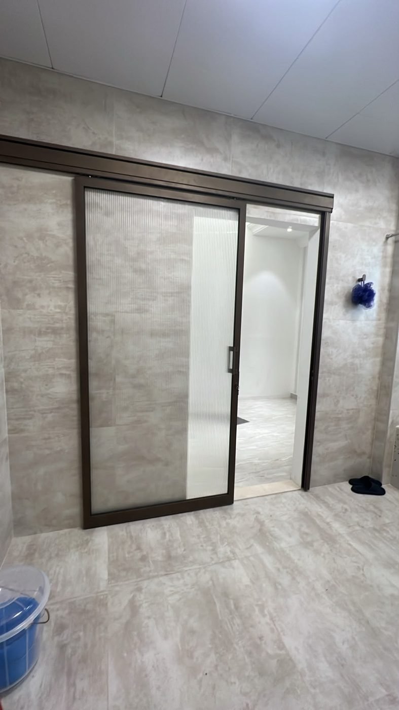 Finished fluted-glass sliding washroom door with bronze frame, UAE