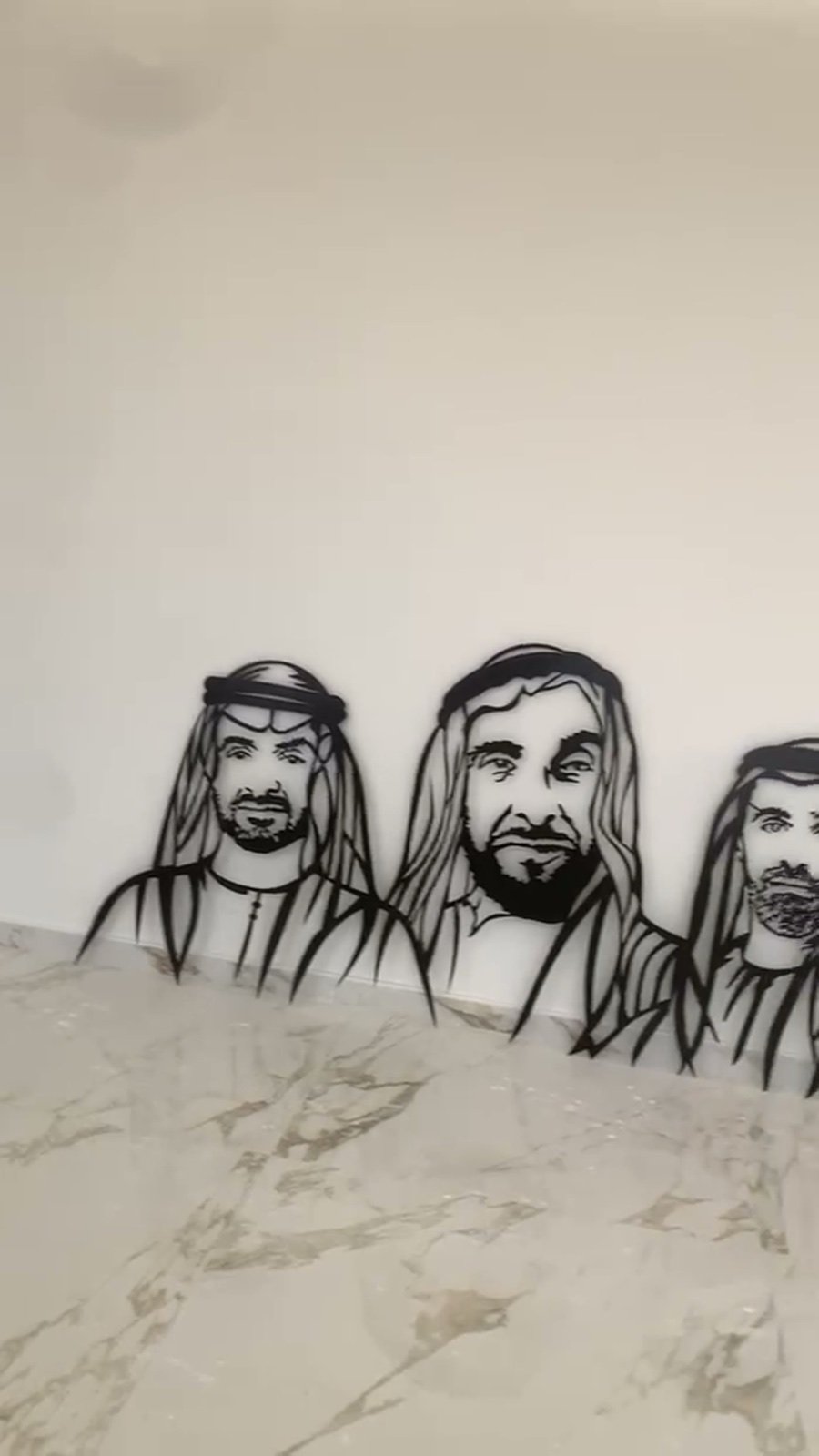 Laser-cut metal portrait sections positioned on the villa wall during installation