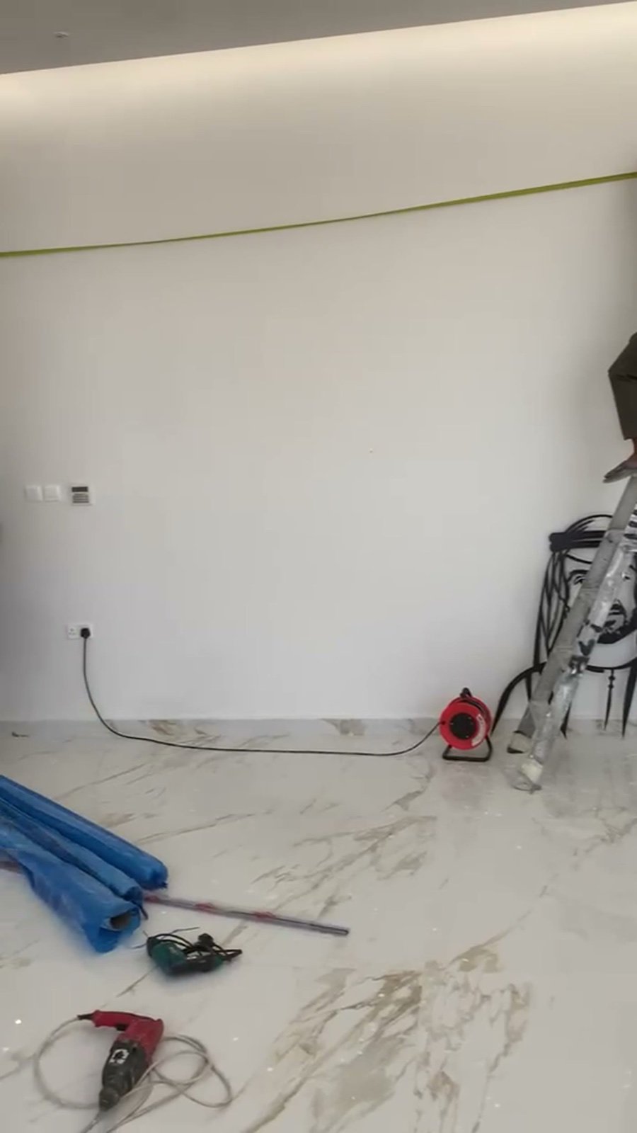 Empty villa reception wall with tools laid out before the metal wall art installation, Abu Dhabi