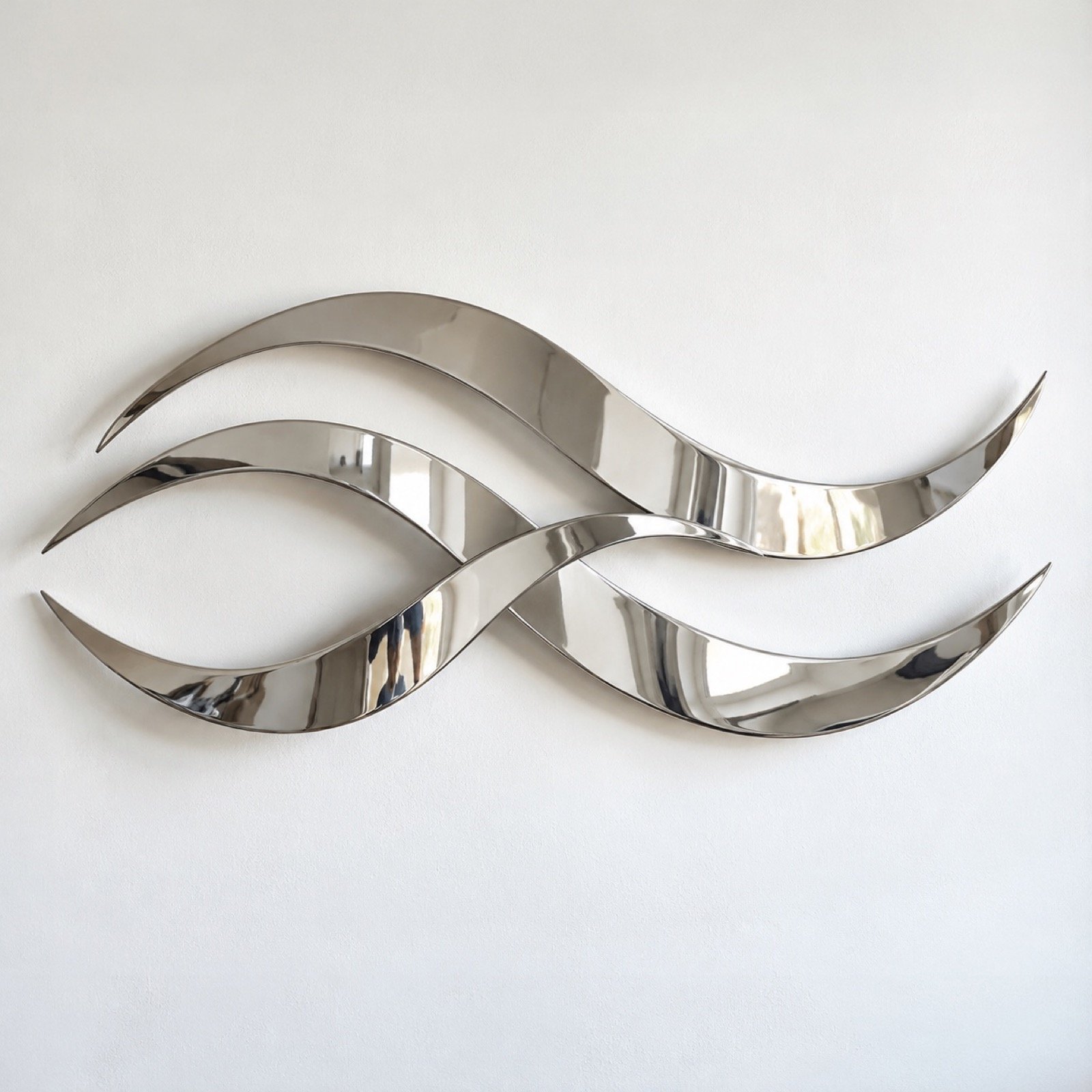 Silver liquid wave wall art with three overlapping stainless-steel ribbons on a white wall.