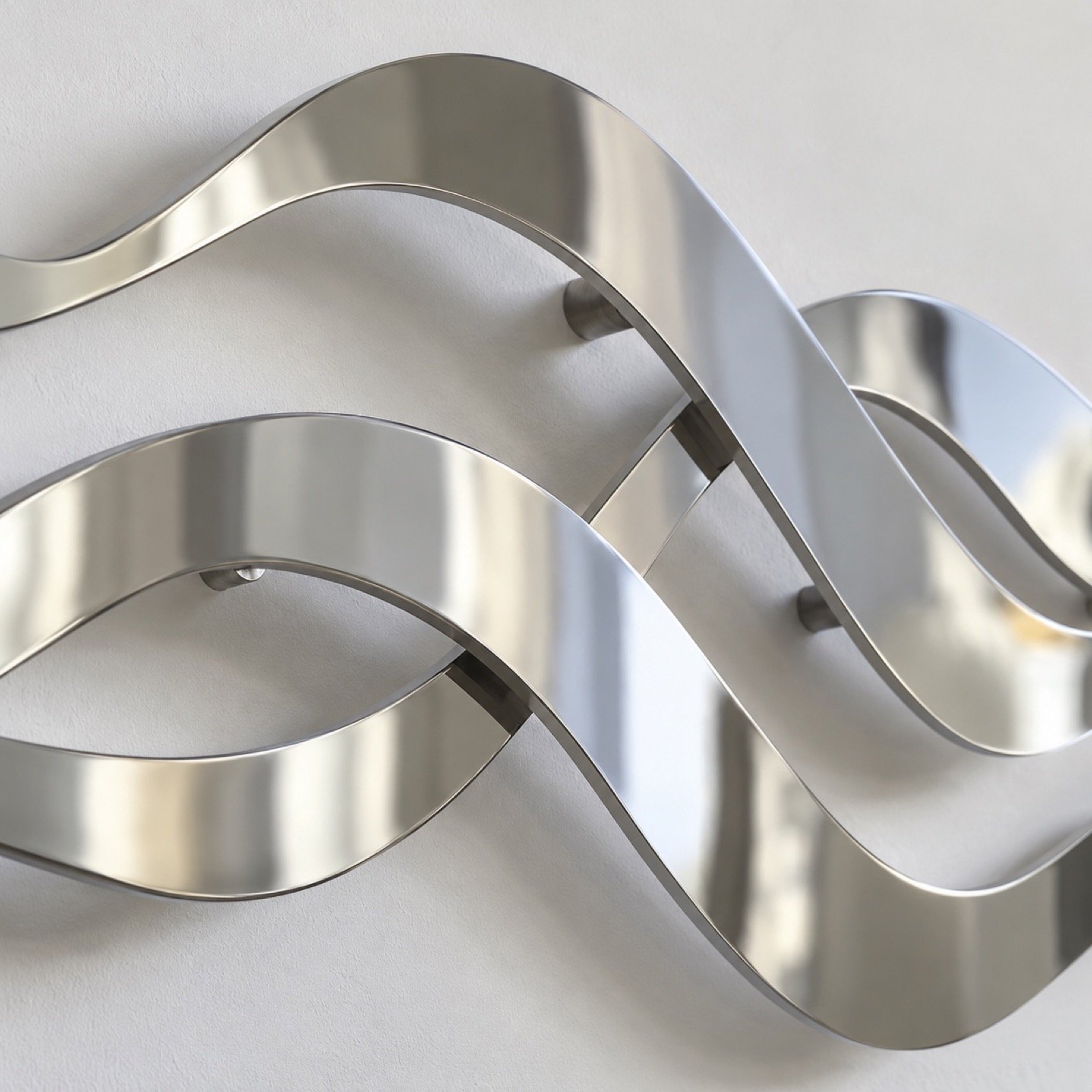 Close-up of the polished silver PVD stainless-steel wave edge and soft wall shadow.