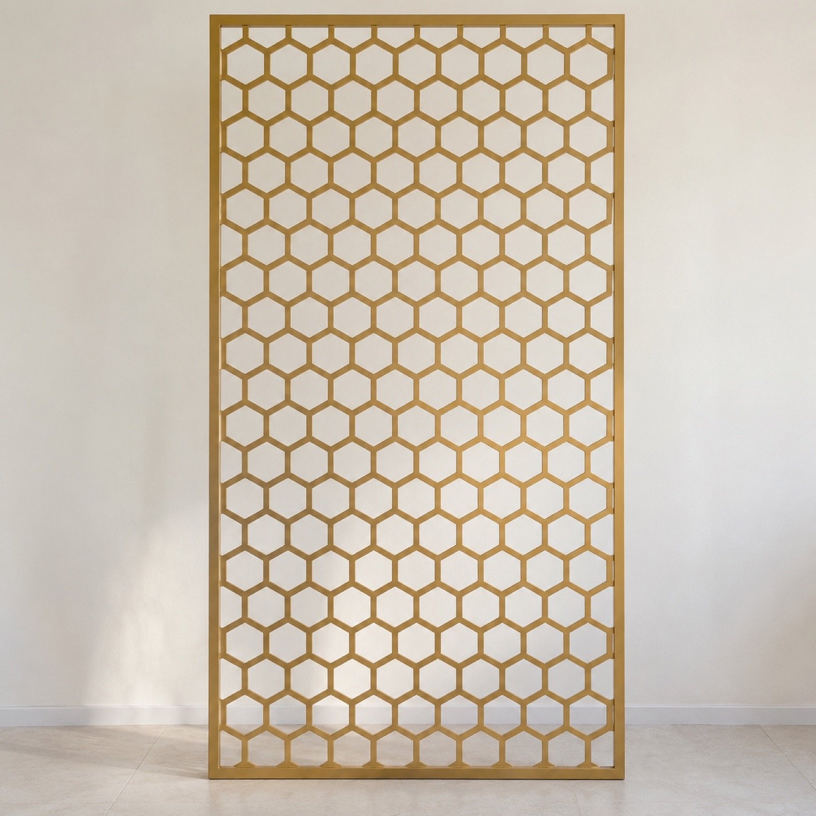 Champagne-gold laser-cut steel hexagon room divider shown straight-on against a plain light wall.