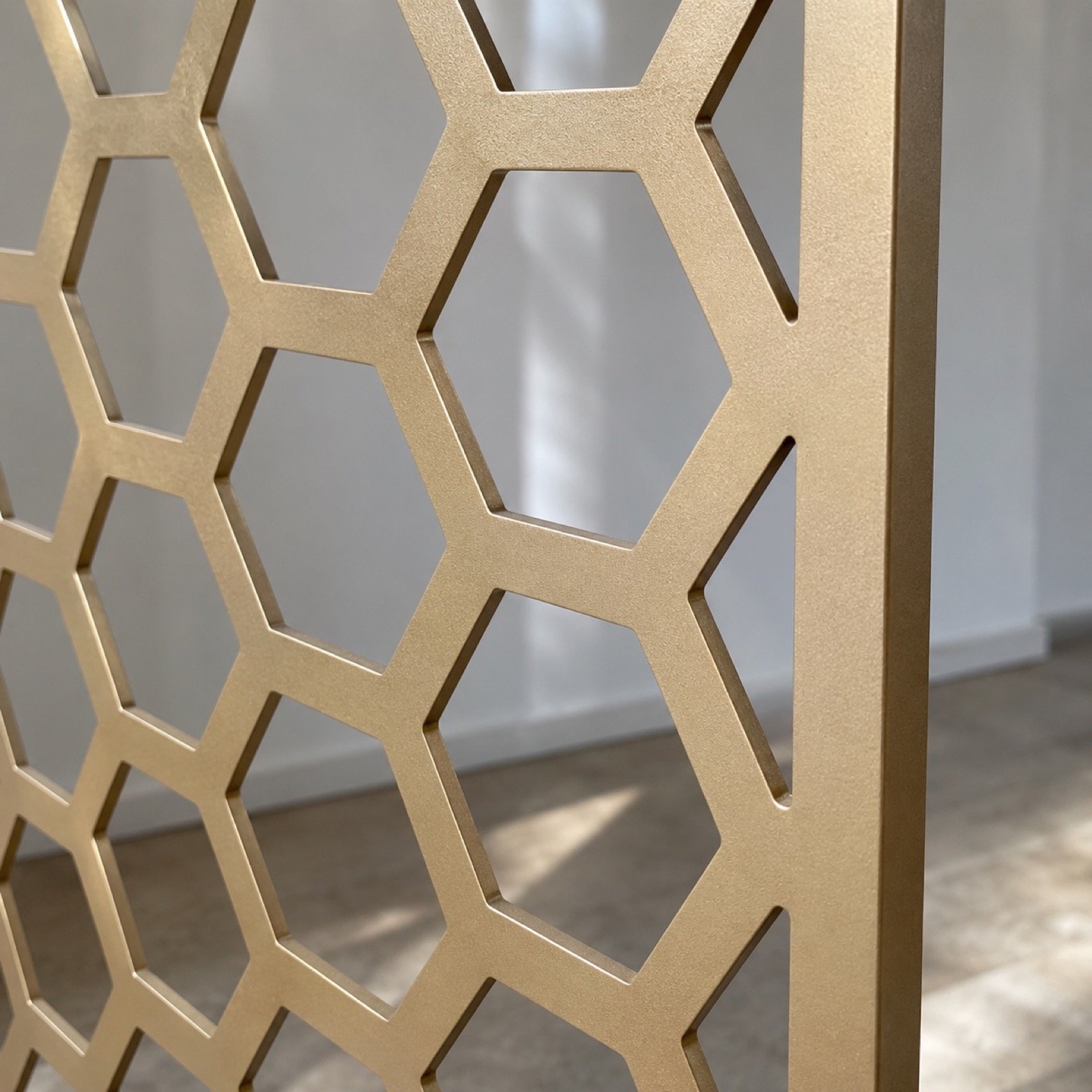 Close-up of the champagne-gold powder-coated steel edge and open hexagon lattice.