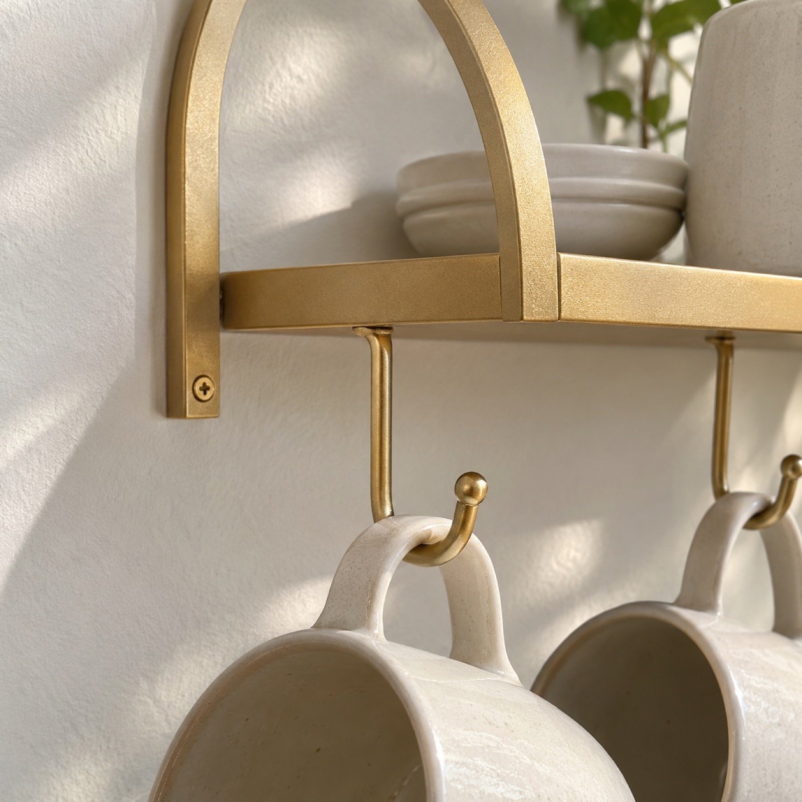 Close-up of satin gold powder-coated steel arch, shelf edge and cup hook