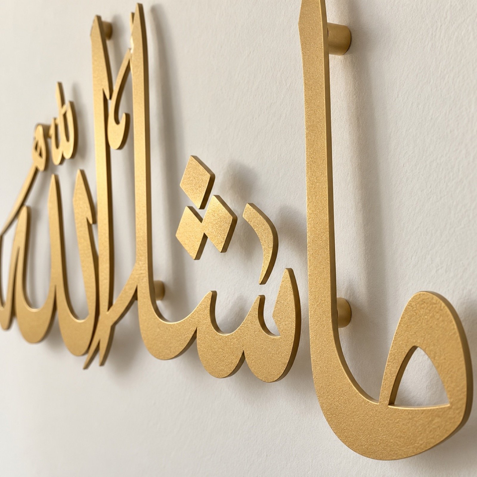 Close-up of the satin gold powder-coated steel calligraphy edge and 2 cm wall stand-off.
