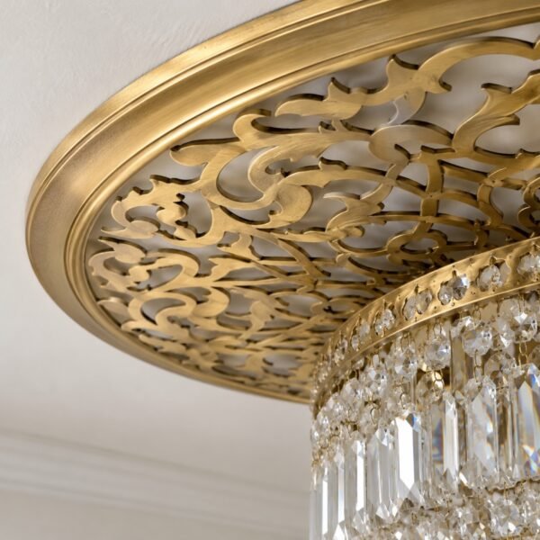 Round gold laser-cut steel ceiling medallion with crystal chandelier on a white wall