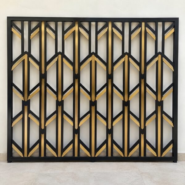 Front view of a black laser-cut aluminium balcony screen with a gold geometric accent on a white wall.