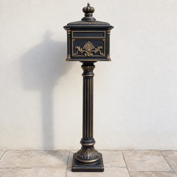 Freestanding black and antique-gold cast aluminium villa mailbox pillar on light paving