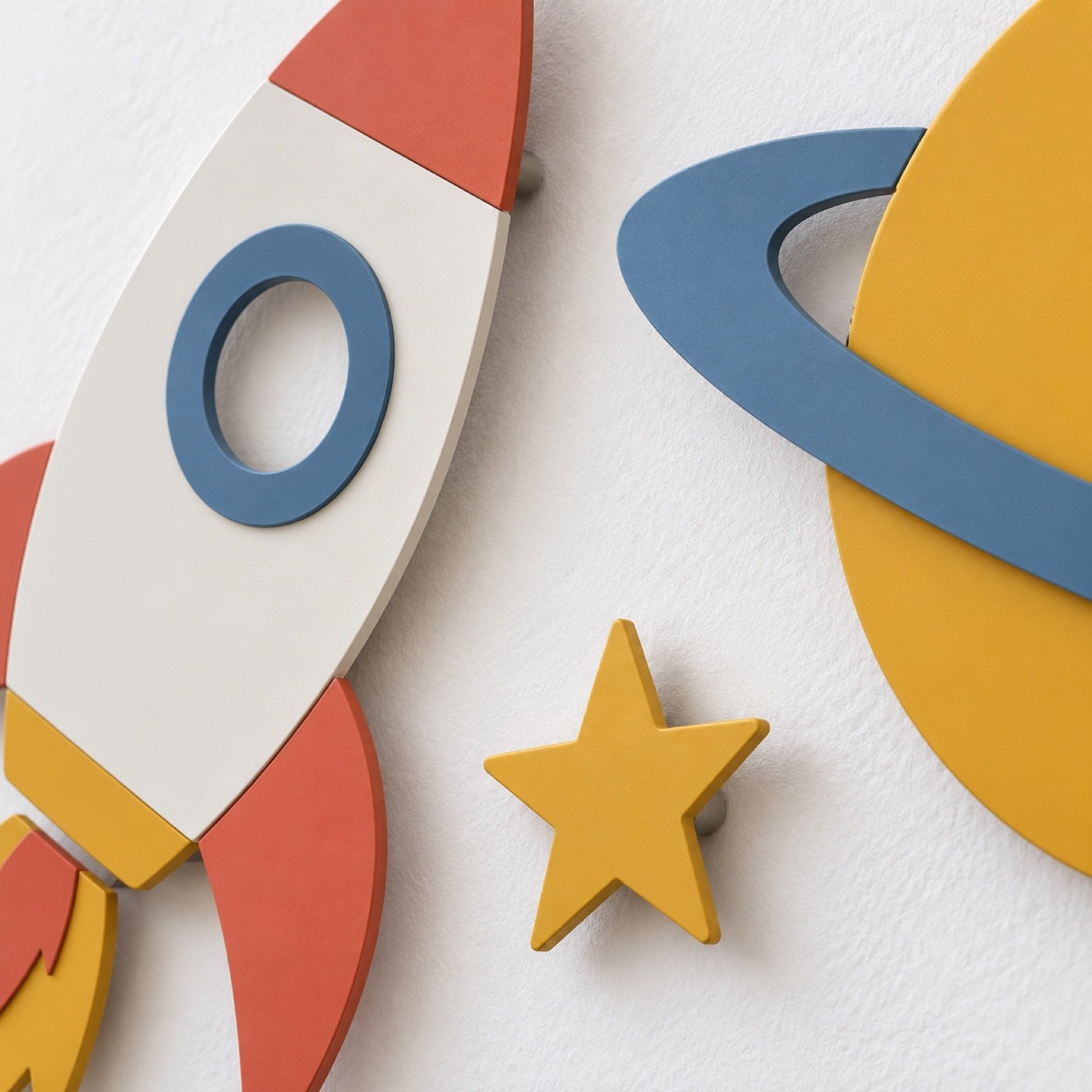 Close-up of powder-coated steel rocket, Saturn ring and star wall pieces