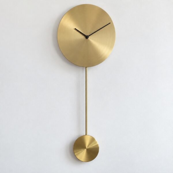 Minimal brass pendulum wall clock with blank round face and black hands on a white wall