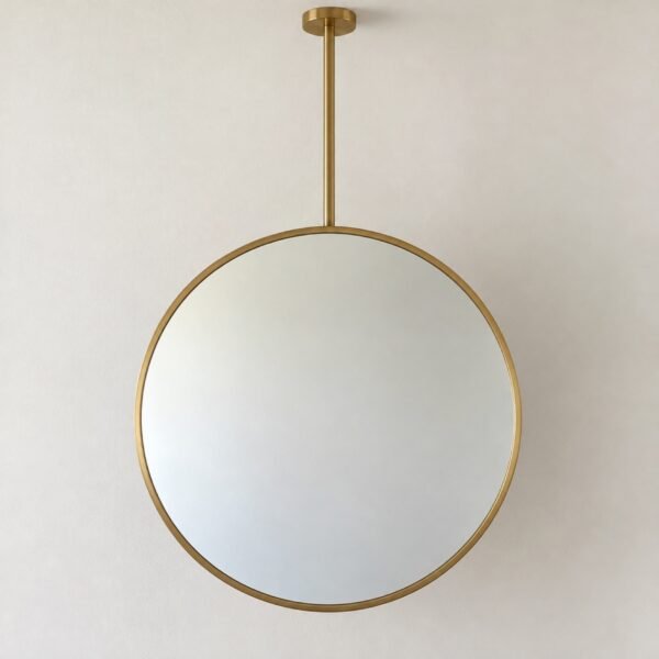 Round brushed brass ceiling-hung pivot vanity mirror on a plain white wall