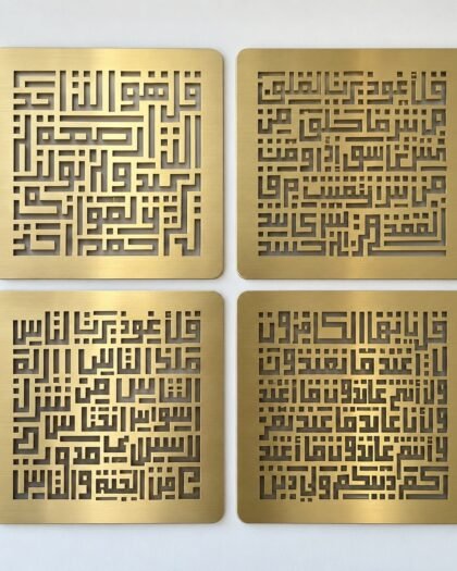 Four brushed champagne-gold PVD steel rounded-square Four Quls calligraphy panels arranged in a 2x2 grid on a white wall.