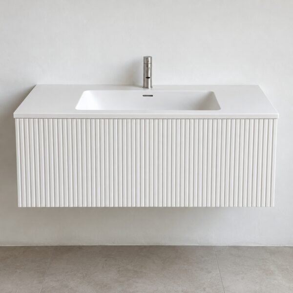 Front view of a matte white fluted Corian floating vanity with integrated basin on a plain white wall.