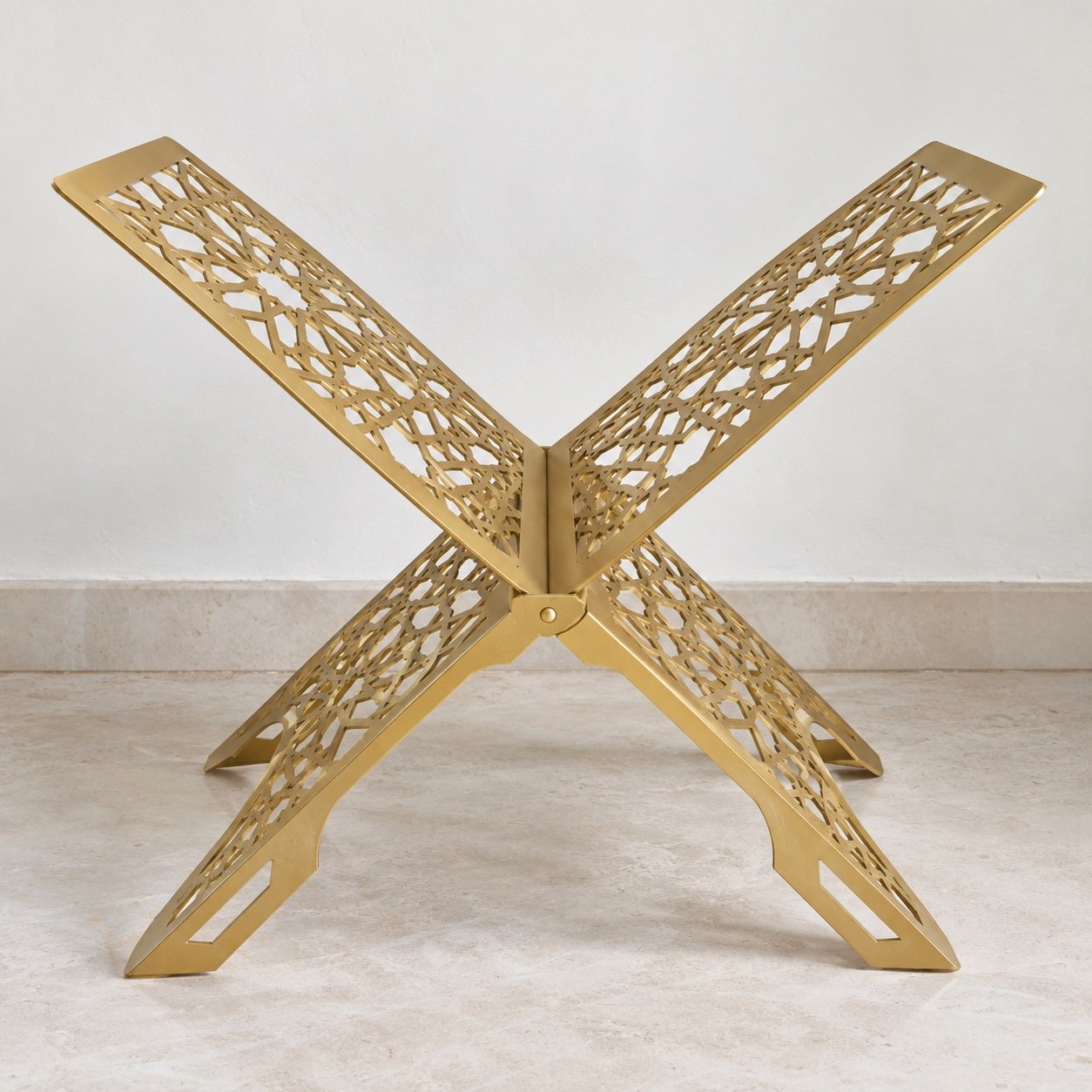 Gold folding steel Quran stand with geometric lattice cut-outs against a plain white wall.