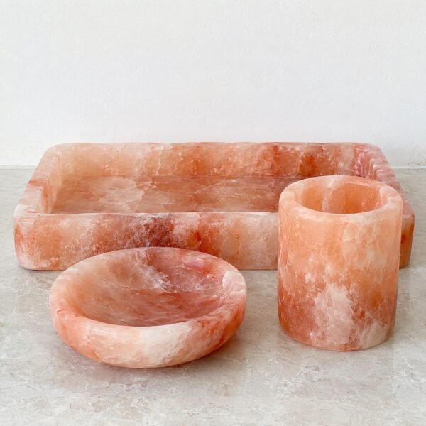 Pink Himalayan salt bathroom accessory set with soap dish tumbler and tray on a plain white background