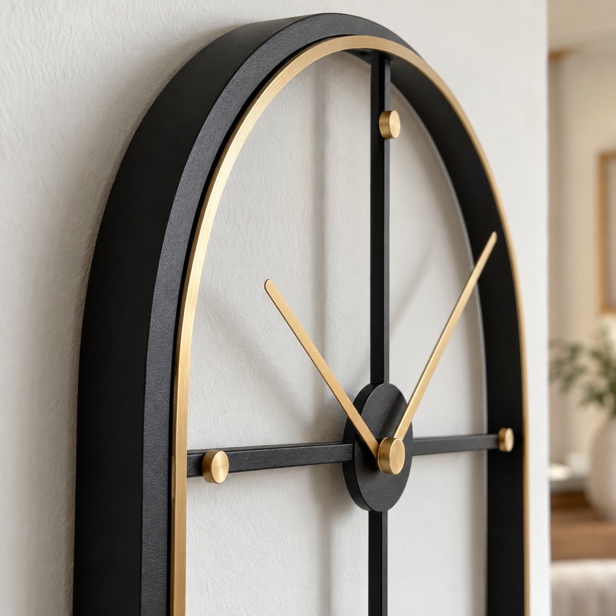 Close-up of the powder-coated black steel edge, gold rim, hands and dot markers on an arch wall clock.