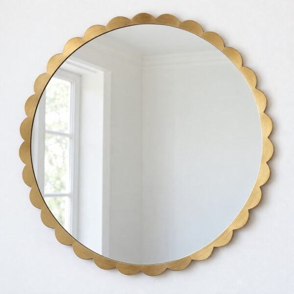 Round scalloped edge gold mirror on a plain white wall, front view