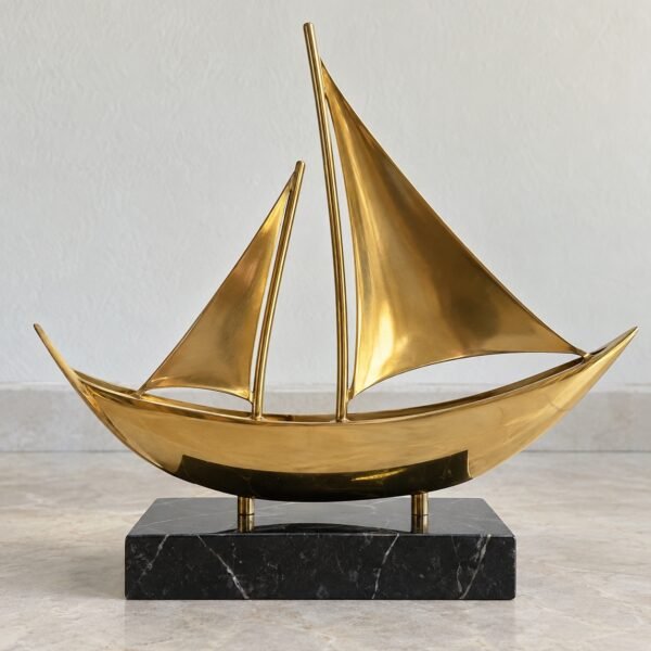 Gold PVD steel dhow desk sculpture on a black marble base against a plain light wall.