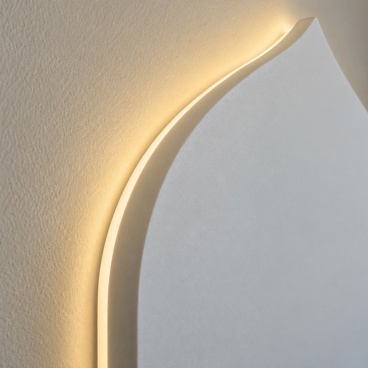 Close-up of the matte white solid-surface mihrab panel edge and soft LED halo