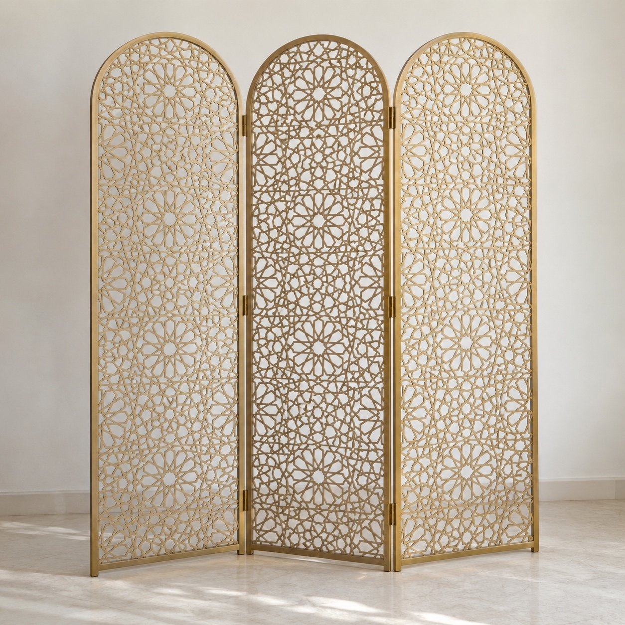 Three-panel champagne-gold arched mashrabiya room divider standing against a light wall