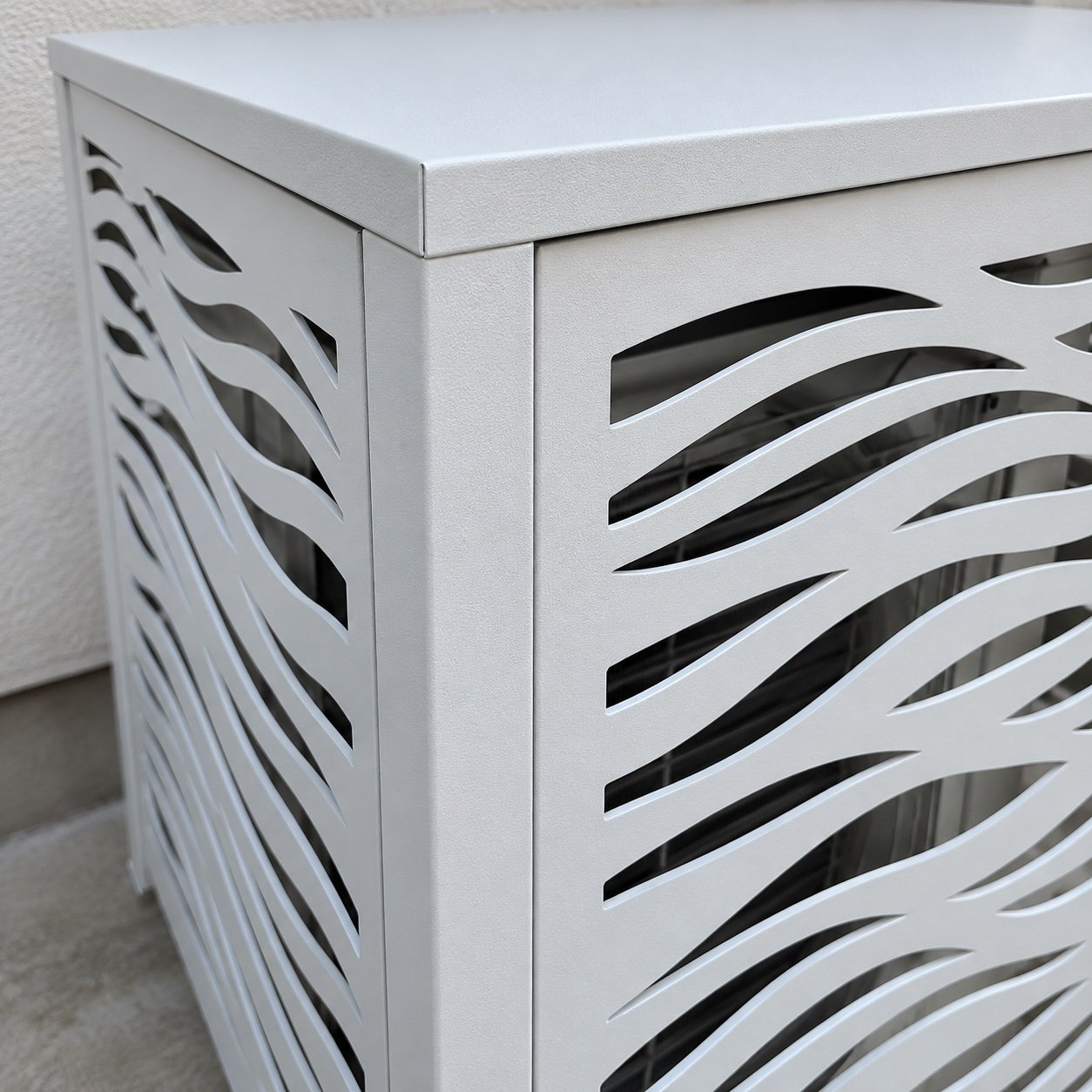 Close-up of white powder-coated metal edge and flowing laser-cut wave pattern