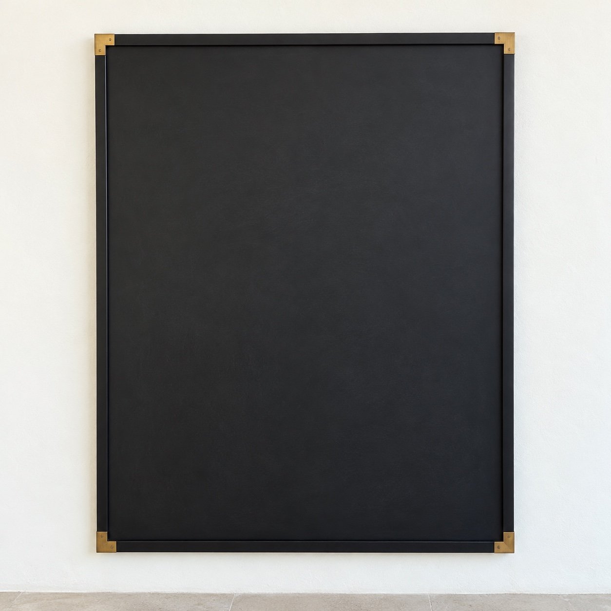 Rectangular black steel cafe menu board frame with gold corners and a blank charcoal chalkboard on a white wall