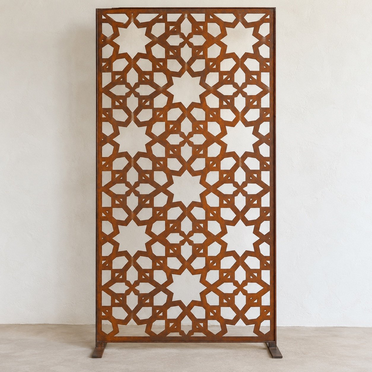 Corten-finish geometric star garden divider panel standing against a plain white wall