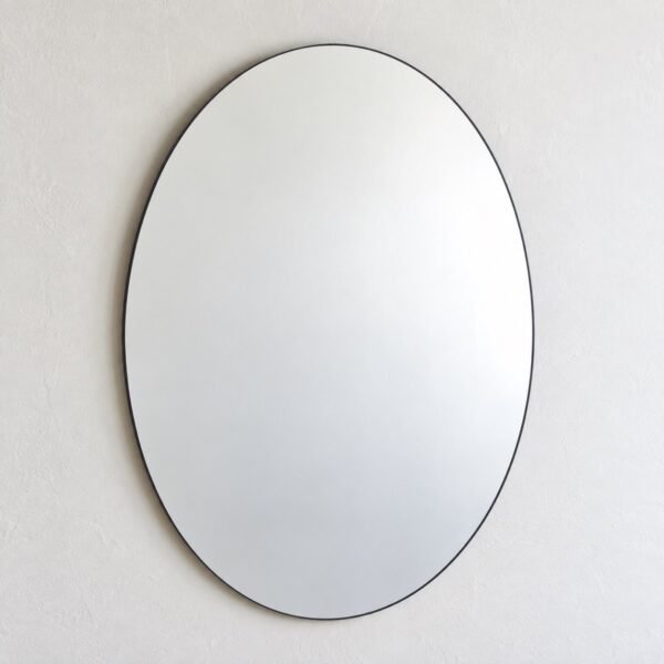 Noor Oval wall mirror with a slim dark charcoal-black metal frame on a white wall