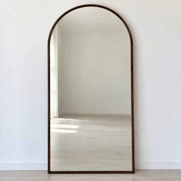 Noor Arch Leaner Mirror with a slim dark walnut-brown wooden frame against a white wall