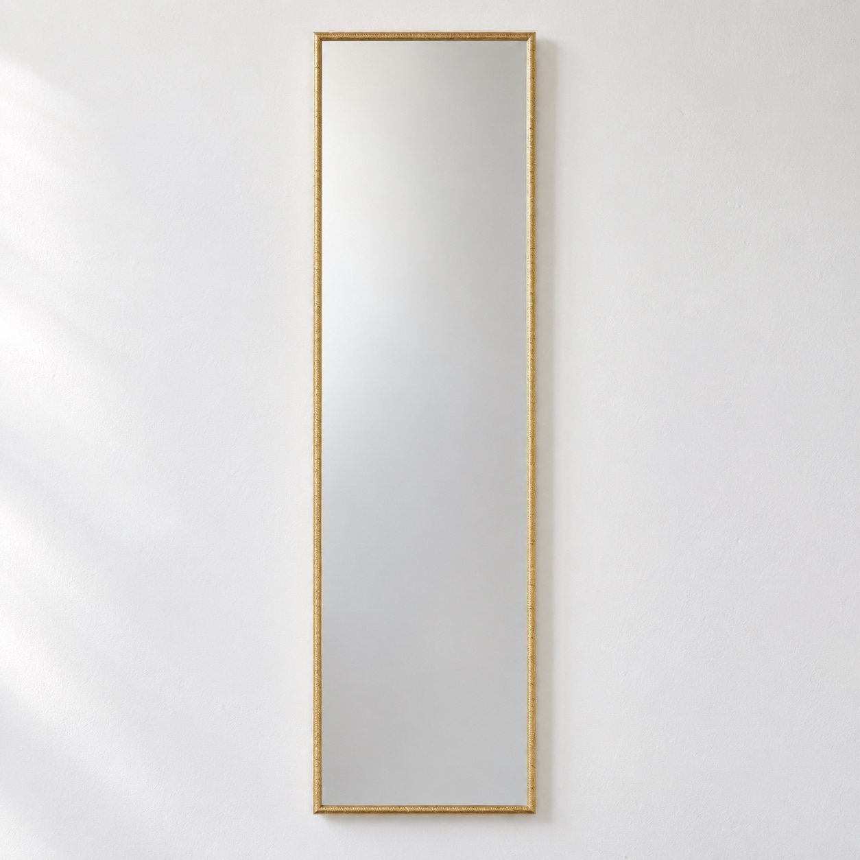 Luma Slim Gold rectangular wall mirror on a plain white wall