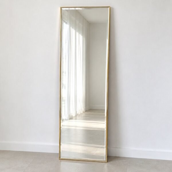 Noura Gold Leaner Mirror with a slim warm-gold frame standing against a white wall