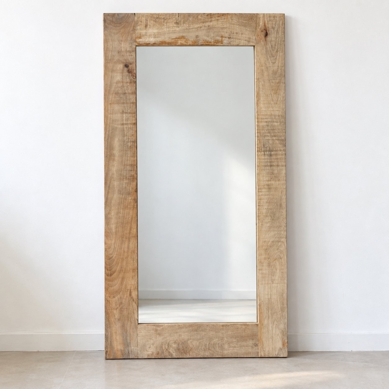 Haya tall rectangular leaner mirror with a broad warm beige natural wood frame against a white wall.