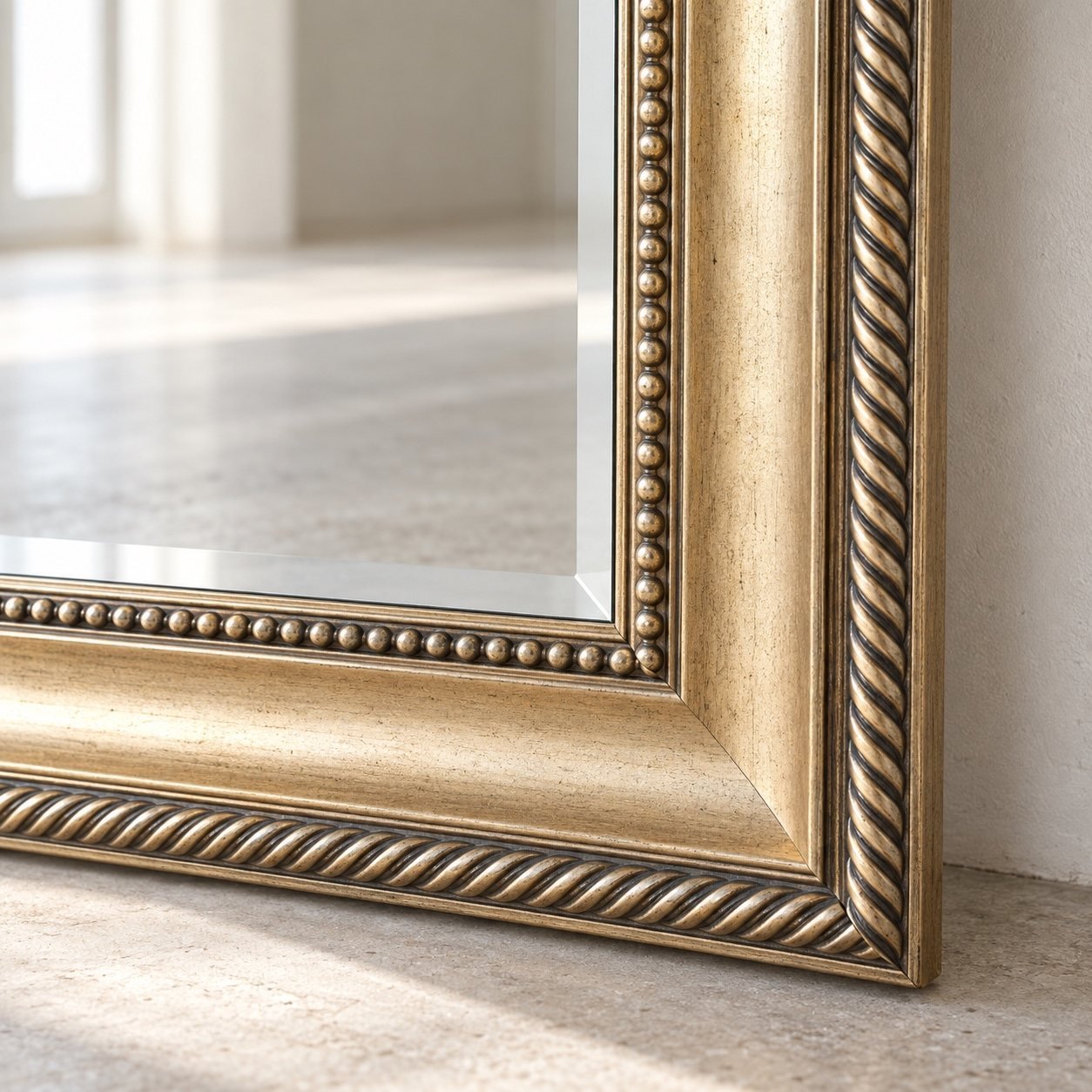 Close-up of Lumea antique champagne-gold frame corner, beaded trim and clear mirror edge
