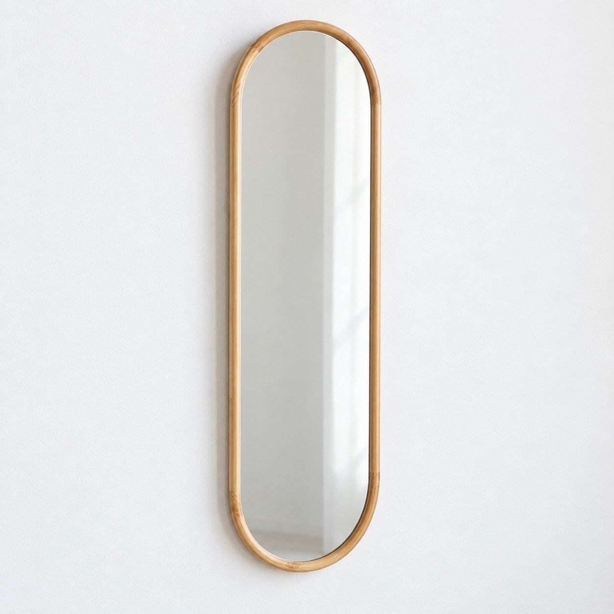 Samaa tall capsule wall mirror with a warm natural wood frame on a plain white wall