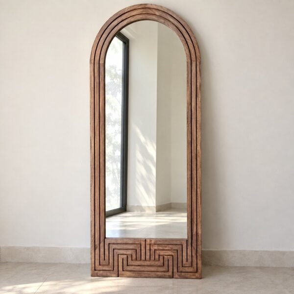 Sahra arched natural wood leaner mirror standing against a plain white wall