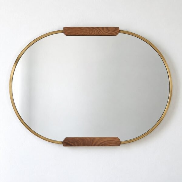 Noor horizontal oval wall mirror with a warm antique-gold rim and walnut wood accents on a white wall