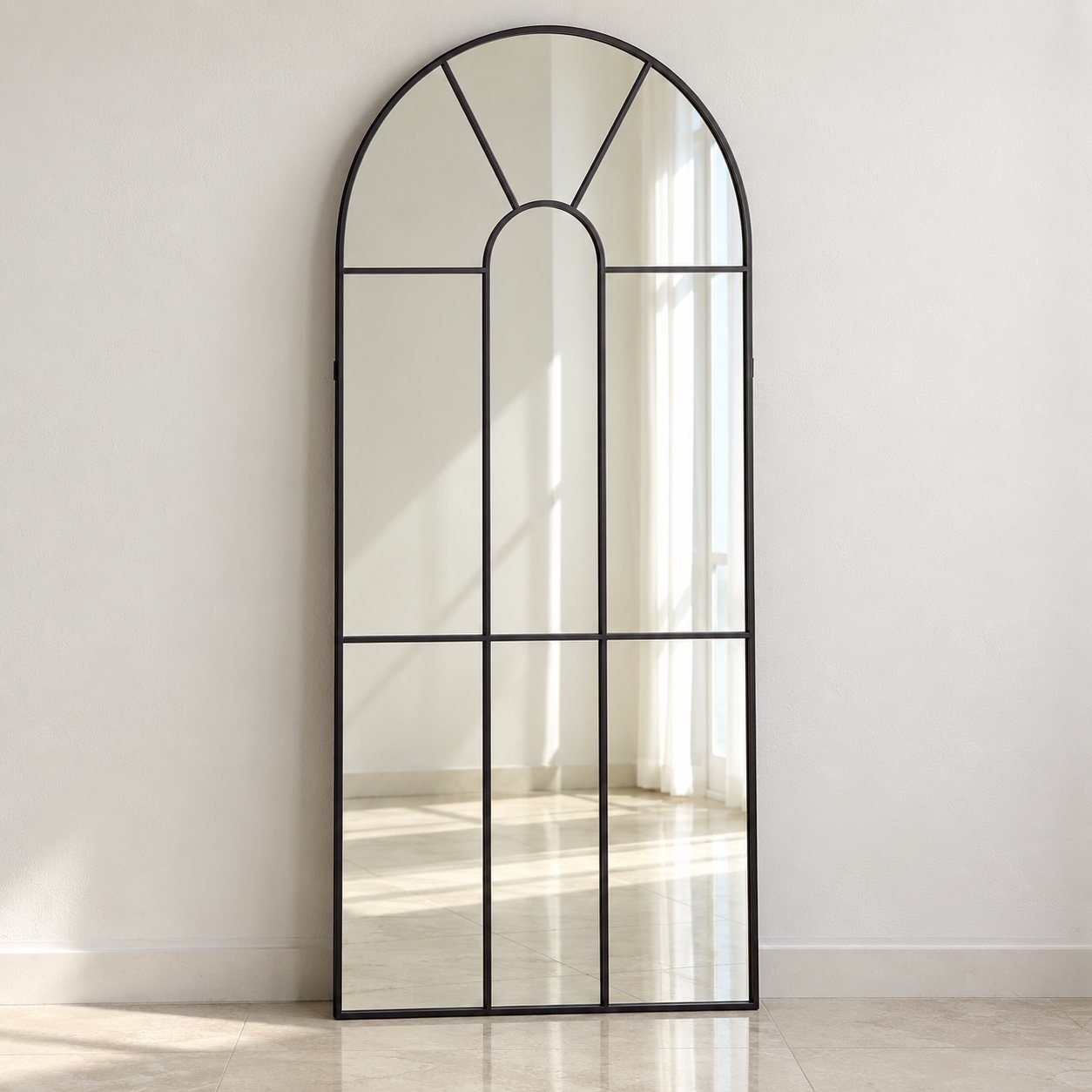 Tall arched grid leaner mirror with charcoal-black metal frame against a plain white wall