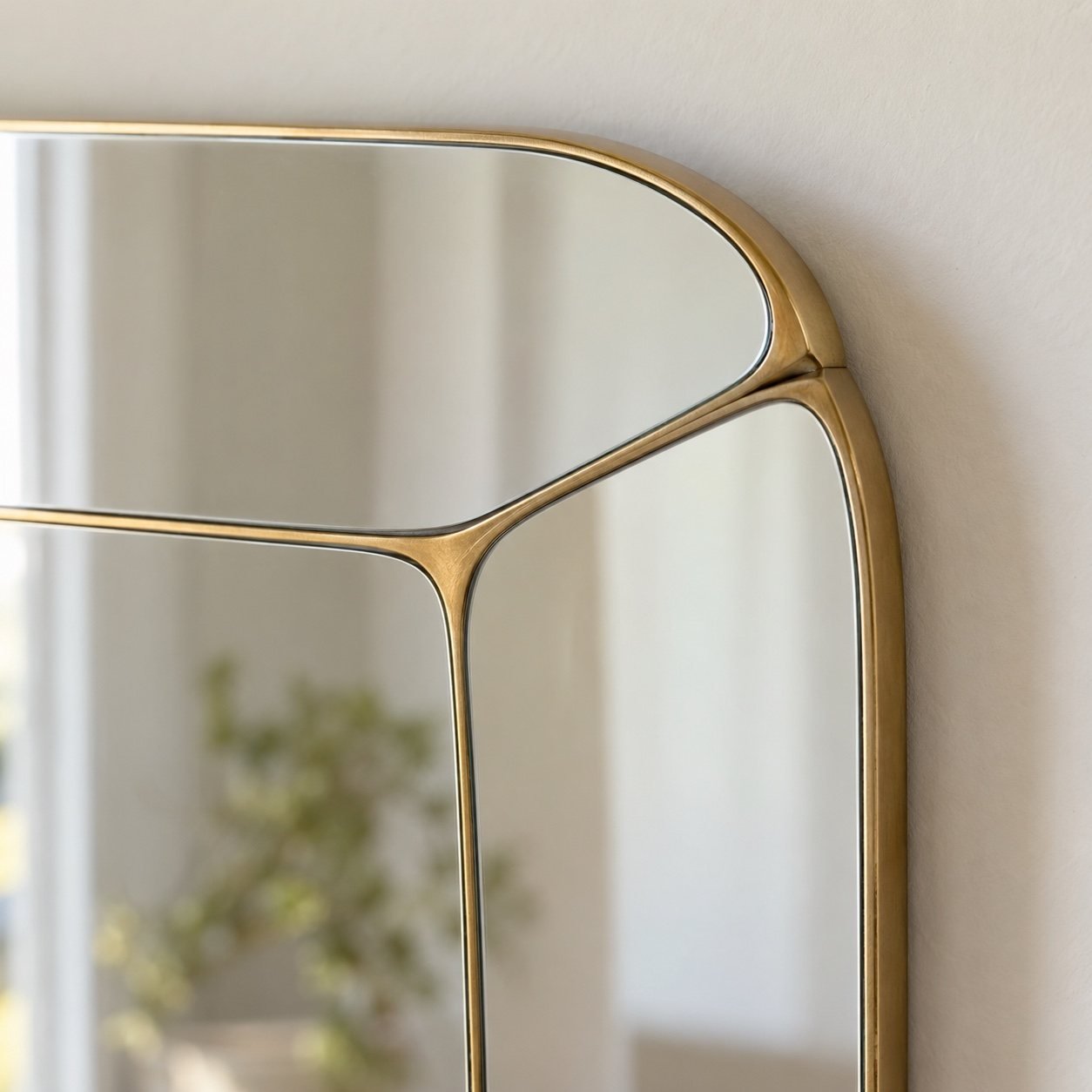 Close-up of the warm champagne-gold metal frame corner and clean mirror edge on Nahla wall mirror.
