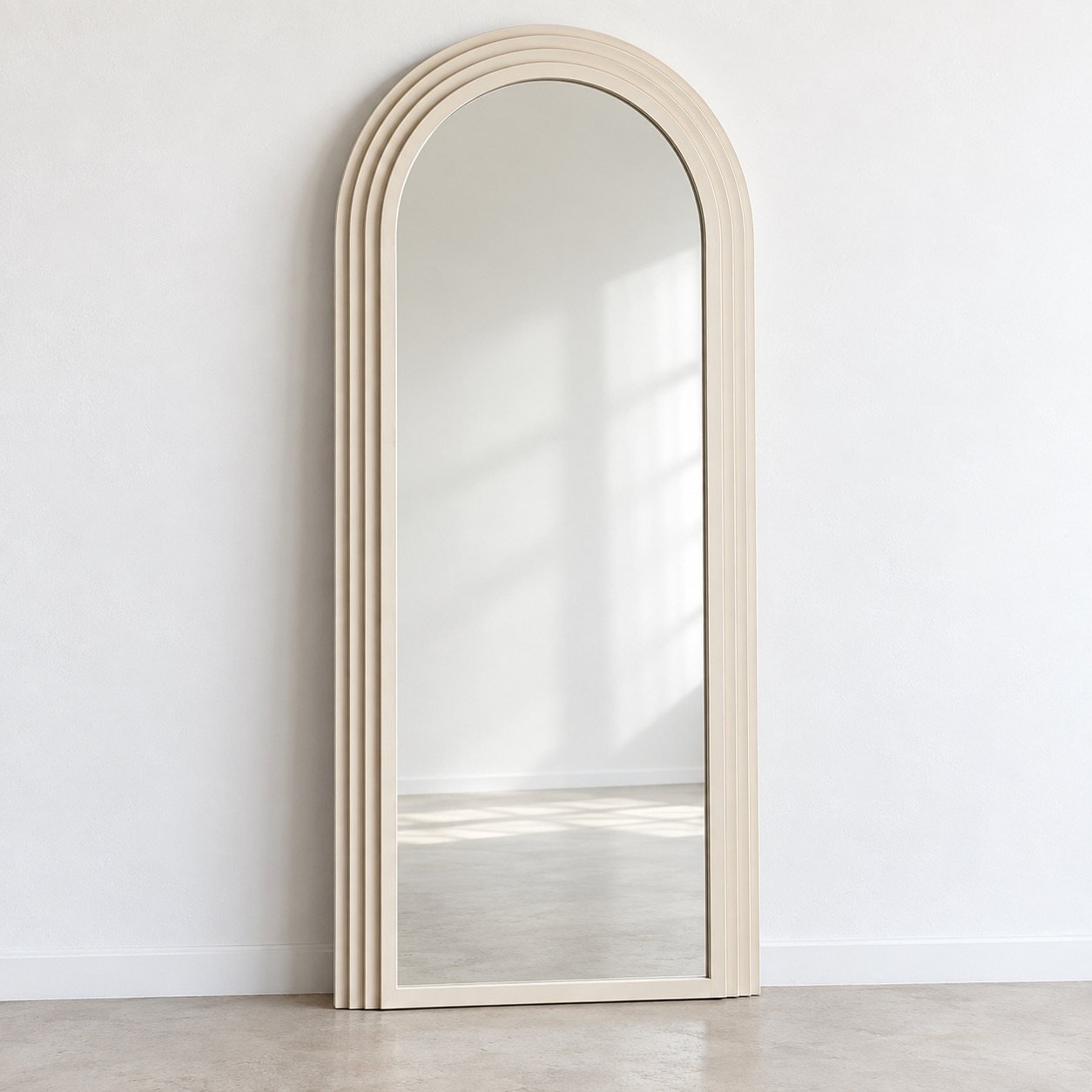 Full-length warm ivory arched leaner mirror against a plain white wall
