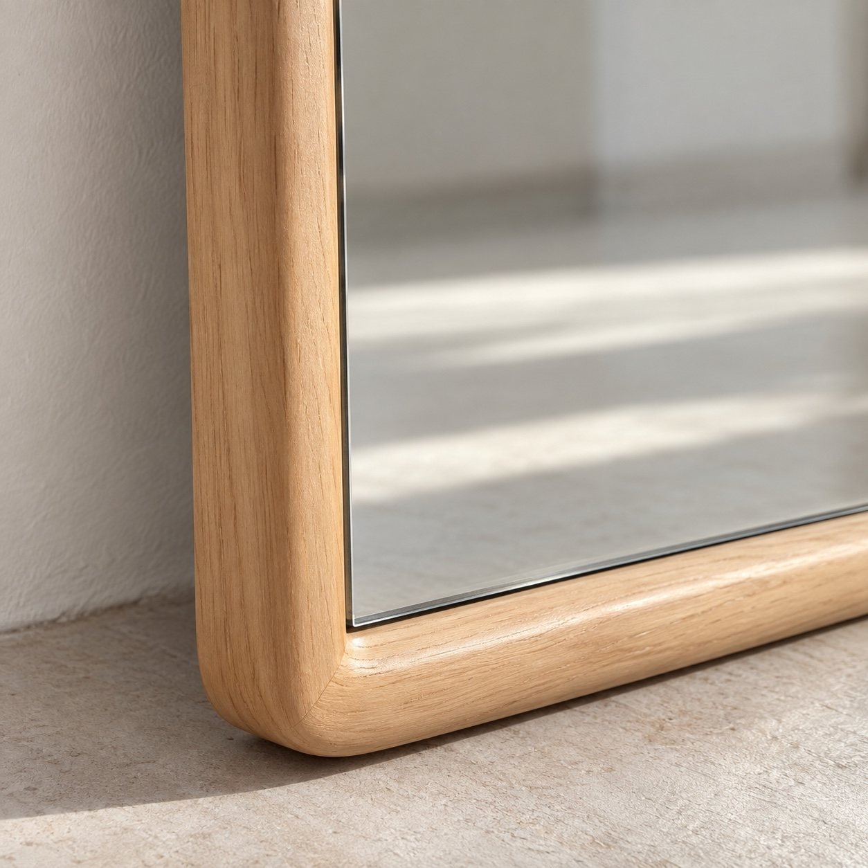 Close-up of the Layan light warm wood frame corner and mirror edge