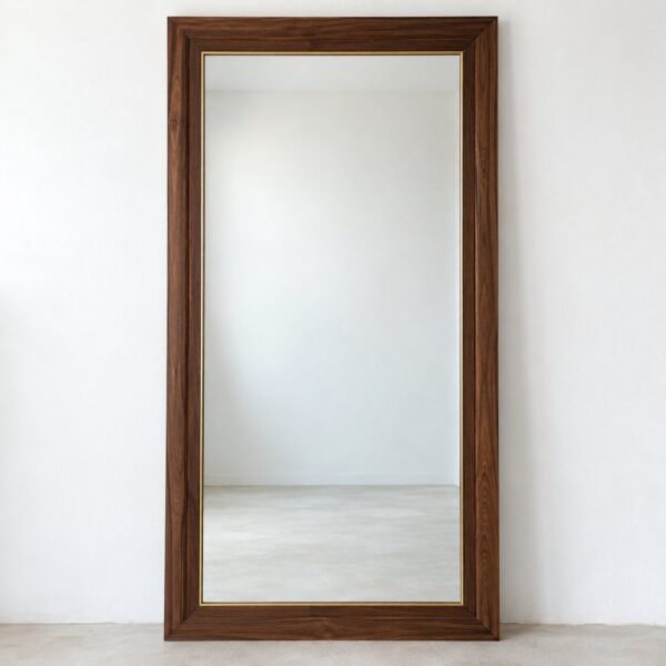 Avenloft rectangular walnut-toned leaner mirror with brass-toned inner trim standing against a plain white wall.