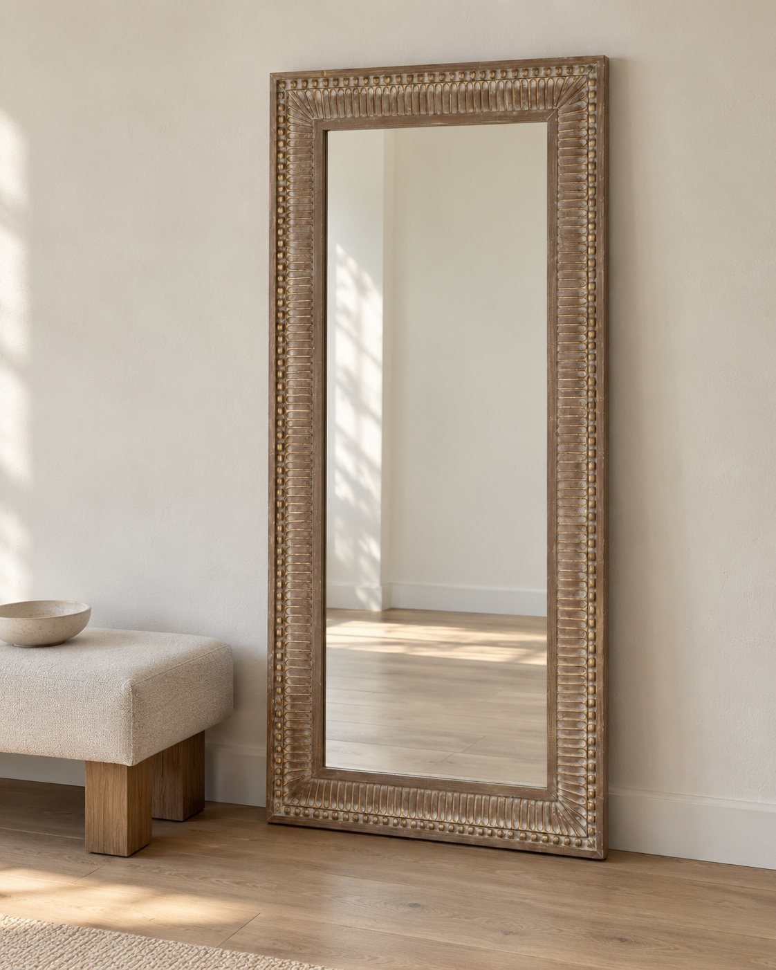 Safa Frame 180x90 cm rectangular leaner mirror beside a simple oatmeal bench in a minimal UAE studio room.