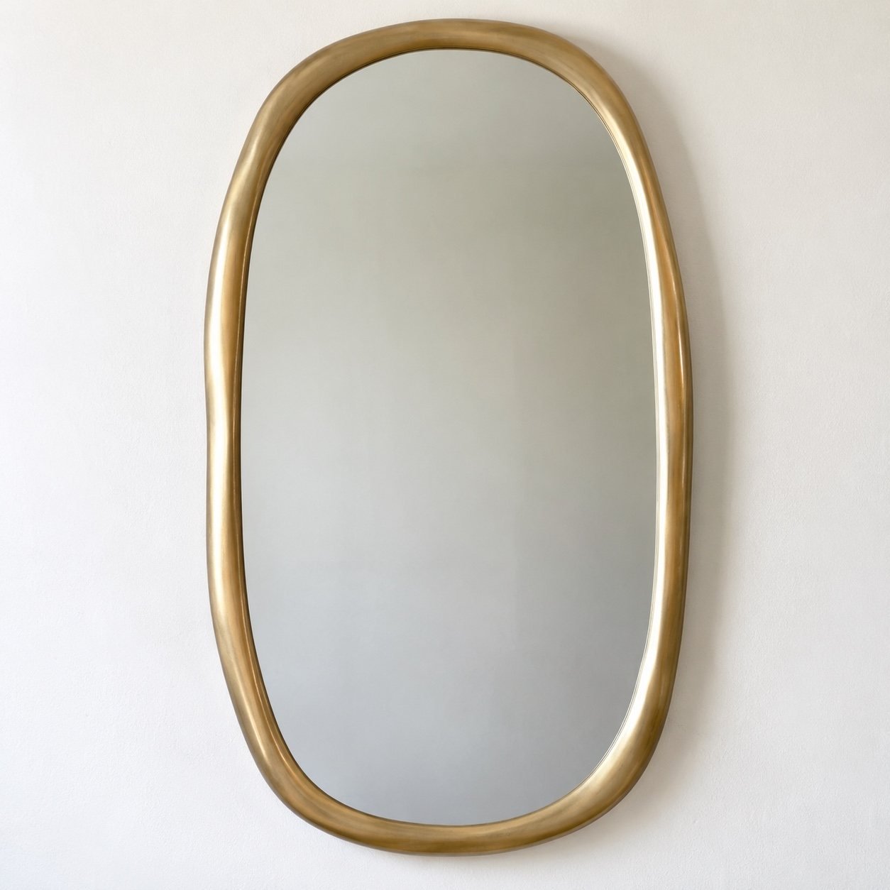 Sahra organic wall mirror with a warm champagne-gold metal frame on a plain white wall.