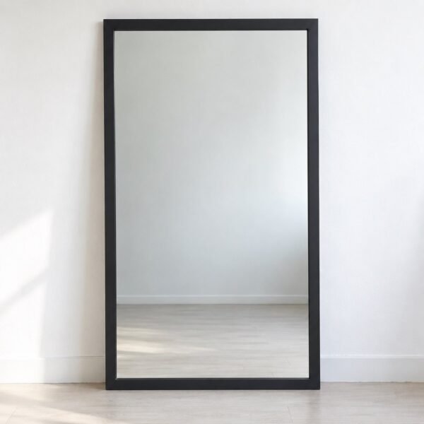 Noura Blackline rectangular leaner mirror with a matte charcoal-black metal frame against a plain white wall.
