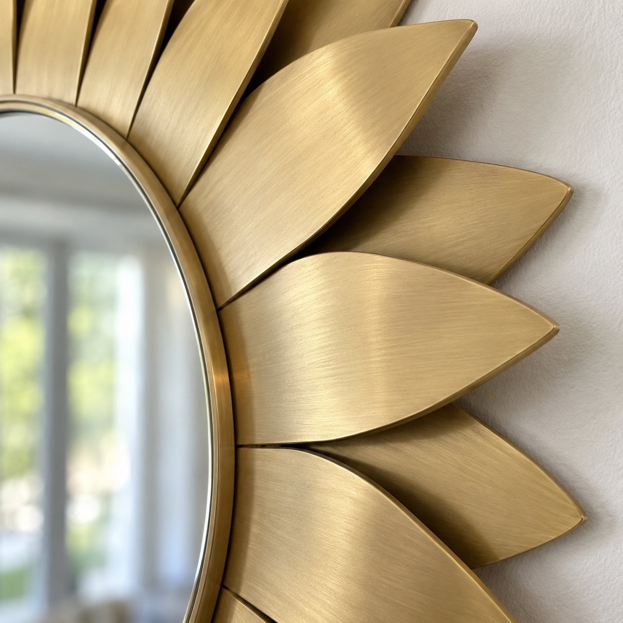 Close-up of the mirror edge and overlapping brushed gold PVD stainless-steel tapered rays showing the material finish.